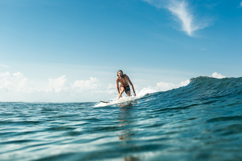vzdálený pohled hezký mužský surfař na koni vlny v oceánu na Nusa Dua Beach, Bali, Indonésie - Fotografie, Obrázek