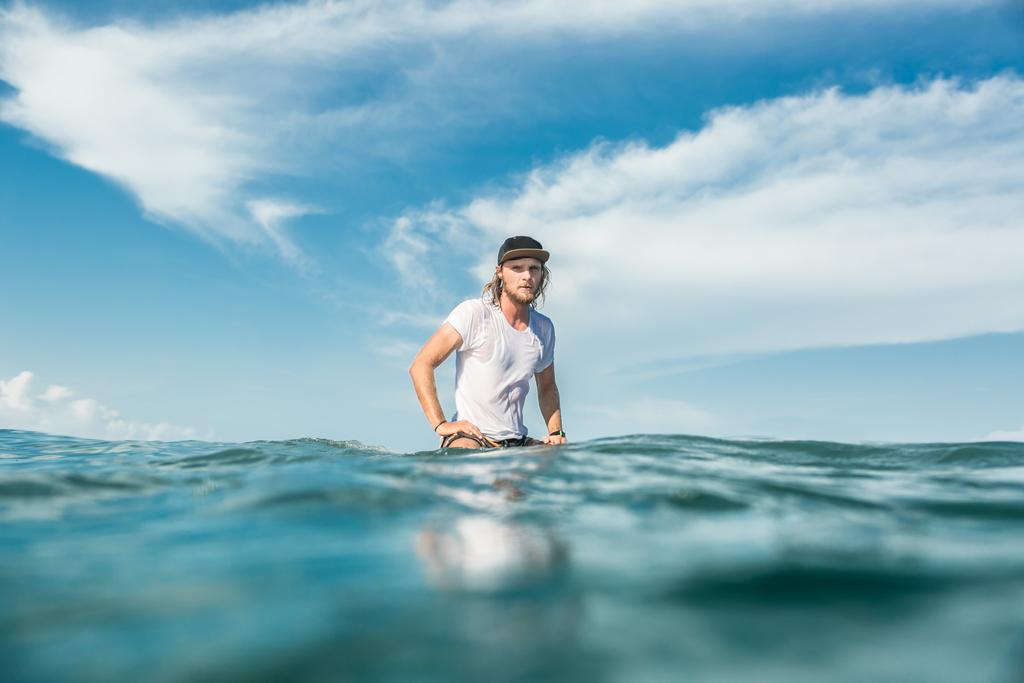 surfer mężczyzna siedzi na pokładzie surfingu w oceanu przy plaży Nusa Dua, Bali, Indonezja - Zdjęcie, obraz
