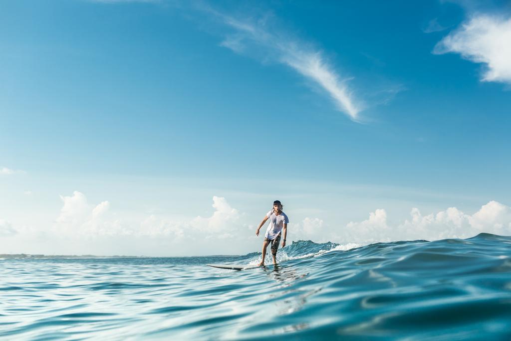 vista a distanza del surfista di sesso maschile cavalcando sul surf in mare a Nusa Dua Beach, Bali, Indonesia
 - Foto, immagini