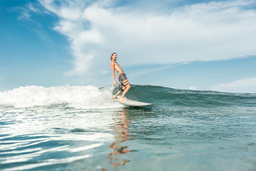 surfista do sexo masculino sem camisa montando ondas no oceano em Nusa Dua Beach, Bali, Indonésia
 - Foto, Imagem