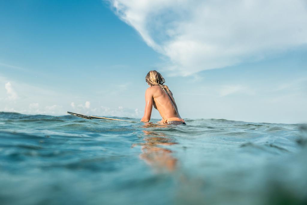 ヌサドゥア ビーチ、バリ、インドネシアの海のサーフィン ボードに水泳上半身裸の男性サーファーの背面図 - 写真・画像