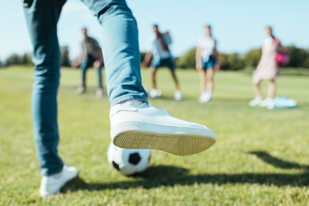 Schnappschuss von Junge, der mit Freunden im Park Fußball spielt - Foto, Bild