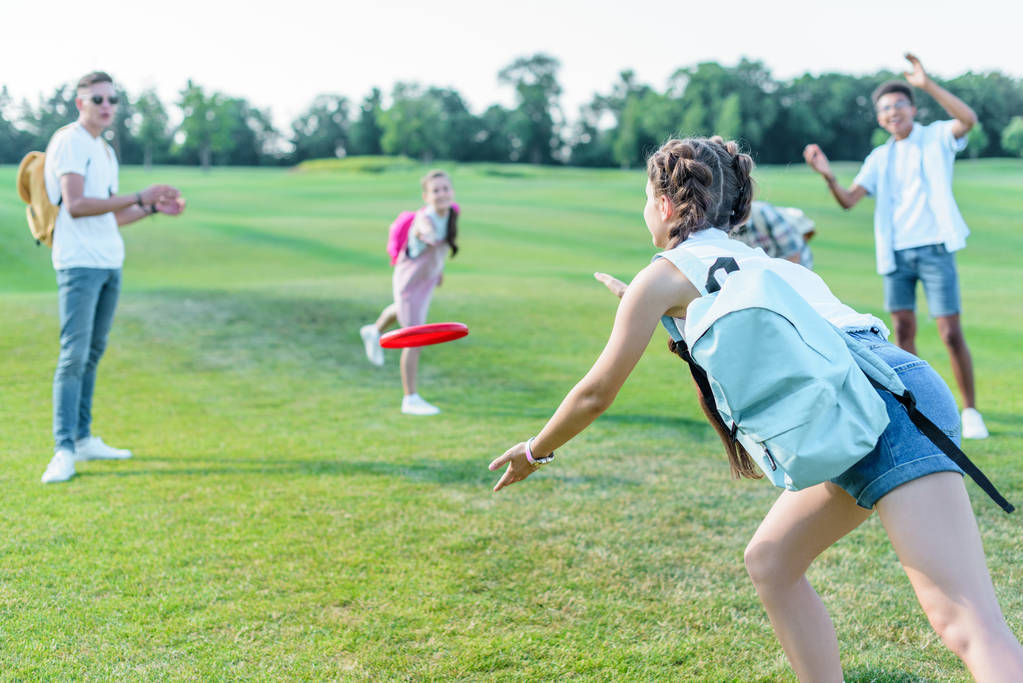 happy multiethnic teenage friends playing with flying disc in park - Photo, Image