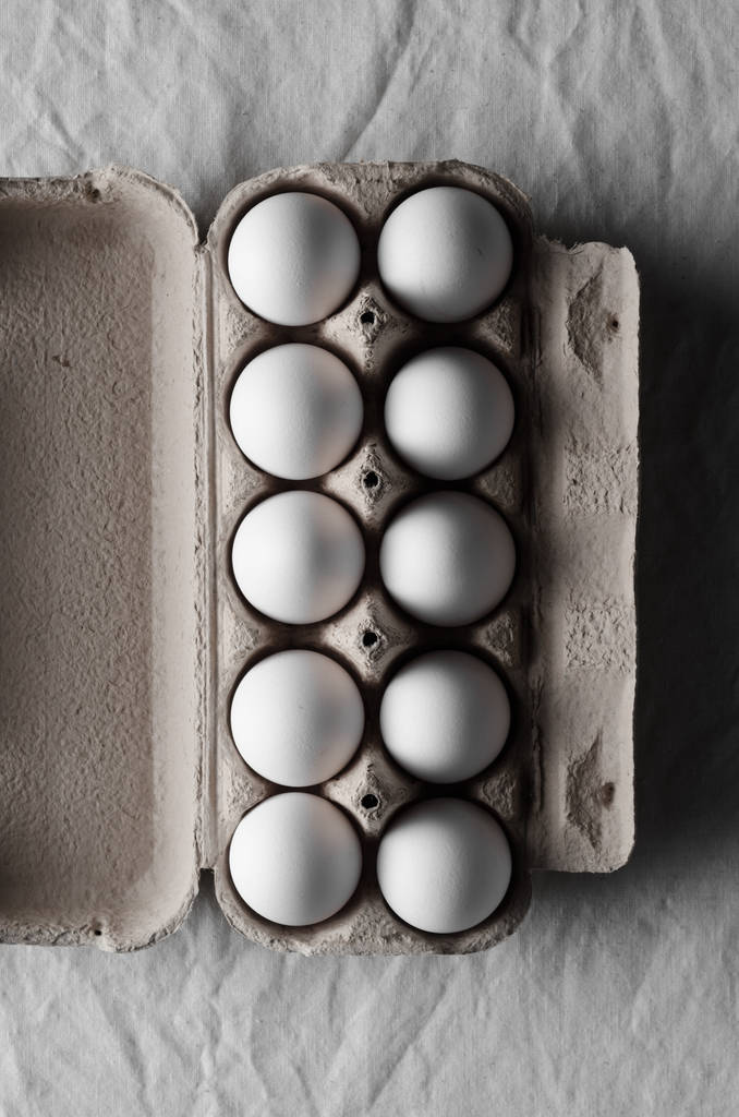Білі яйця в яєчній коробці. фон білої лляної скатертини
. - Фото, зображення