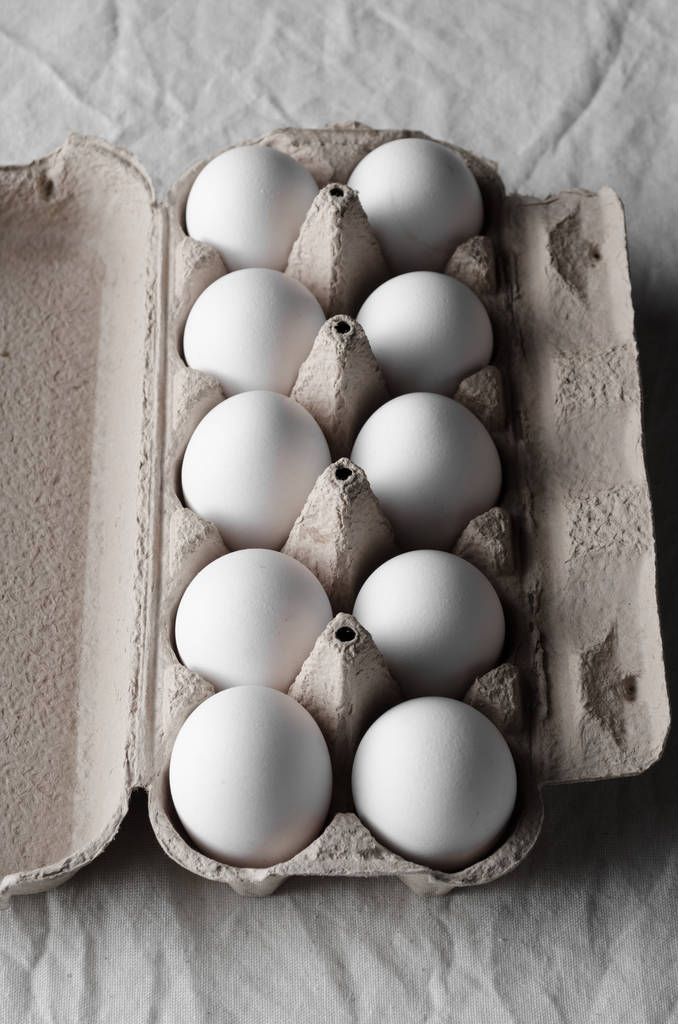 Uova bianche in una scatola di uova. tovaglia di lino bianco sfondo
. - Foto, immagini
