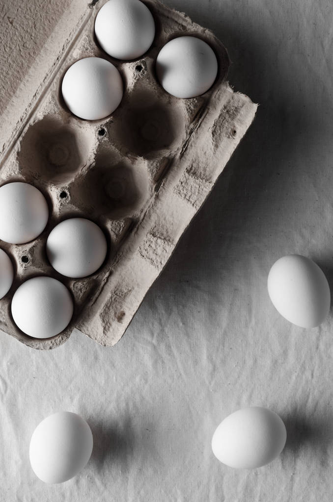 Œufs blancs dans un carton d'œufs. Nappe en lin blanc fond
. - Photo, image