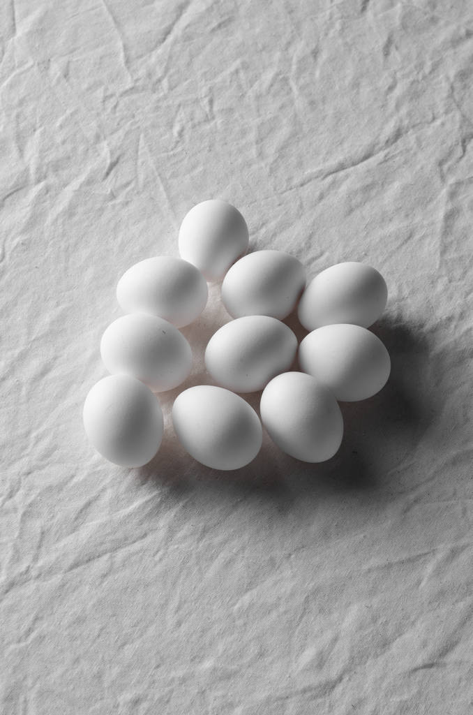 weiße Eier auf einem weißen Leinentischtuch Hintergrund. - Foto, Bild