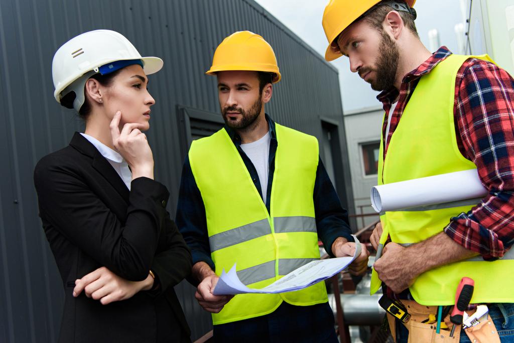 Ingénieur féminin et travailleurs masculins avec des plans parlant de construction
 - Photo, image