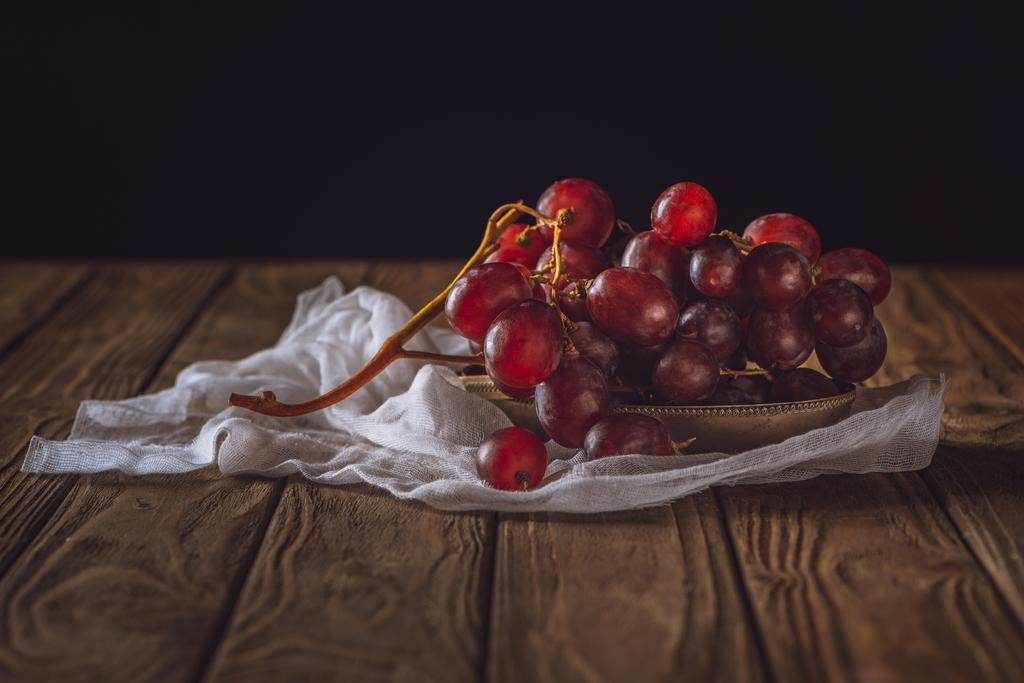 primer plano de uvas maduras sobre mantel de queso y sobre mesa rústica de madera sobre negro
 - Foto, imagen