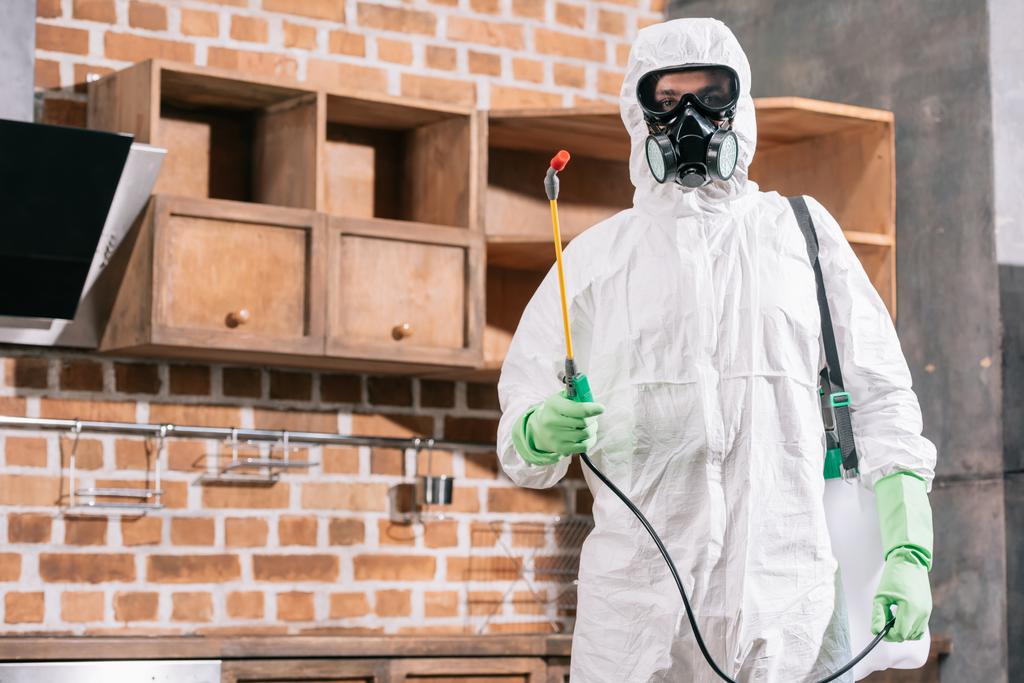 tuholaistorjunta työntekijä univormussa seisoo sumutin keittiössä
 - Valokuva, kuva