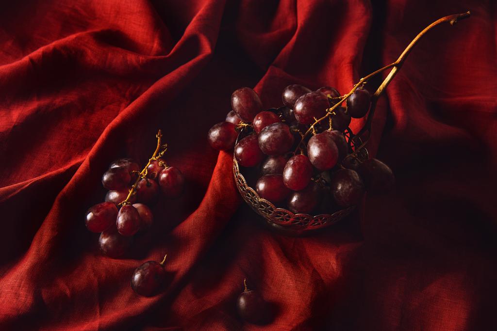 крупним планом знімок свіжого винограду в старовинній металевій мисці на червоній драпіровці
 - Фото, зображення