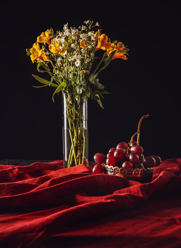 vida morta de uvas em boliche metálico com flores em vaso em cortinas vermelhas
 - Foto, Imagem