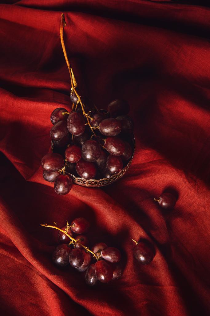 Close-up shot van druiven in vintage metalen kom op rode gordijnen - Foto, afbeelding