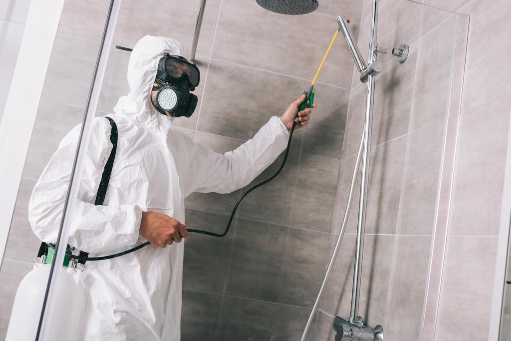 trabajador de control de plagas pulverización de pesticidas con pulverizador en el baño
 - Foto, Imagen