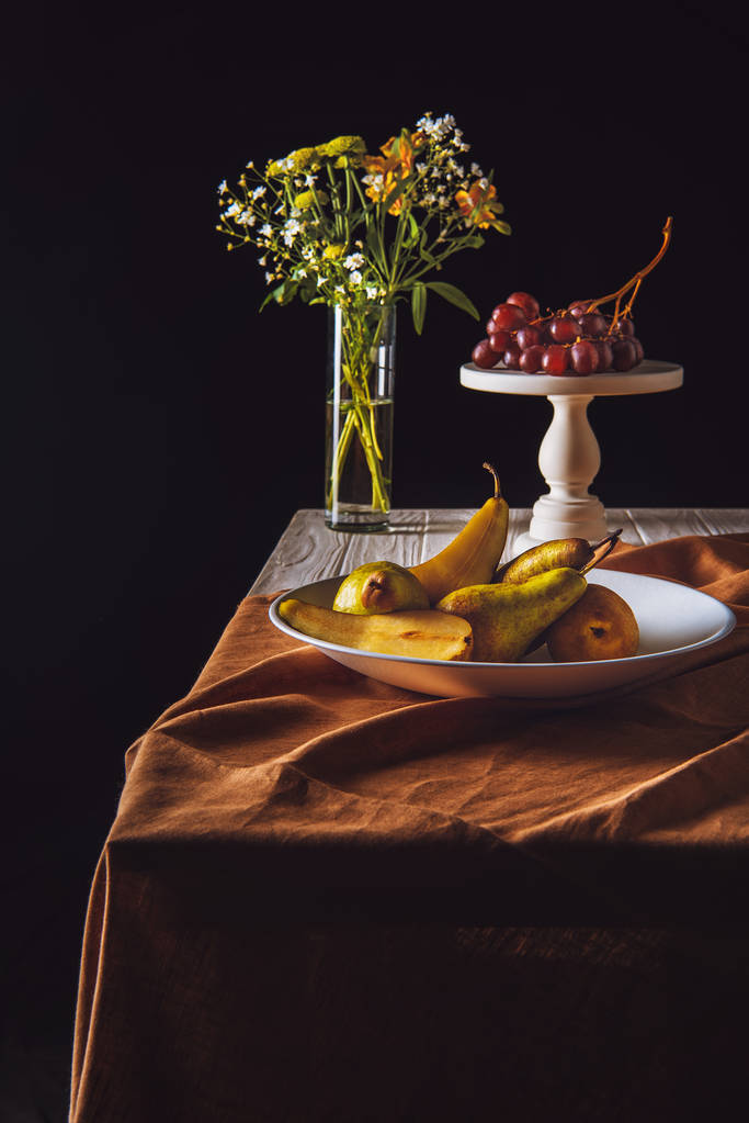 梨と葡萄と黒のテーブル上の花瓶スタンド プレート - 写真・画像
