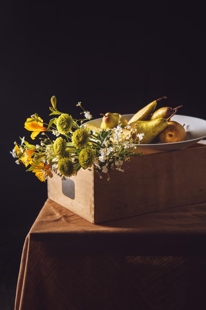close-up shot of bouquet of field flowers with pears in box on black - Photo, Image