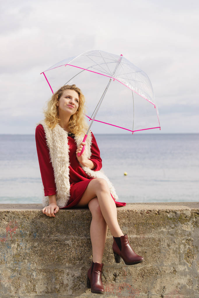 Boldog elegáns felnőtt nő kezében átlátszó esernyő az égre. Időjárás-előrejelzés koncepciója. - Fotó, kép