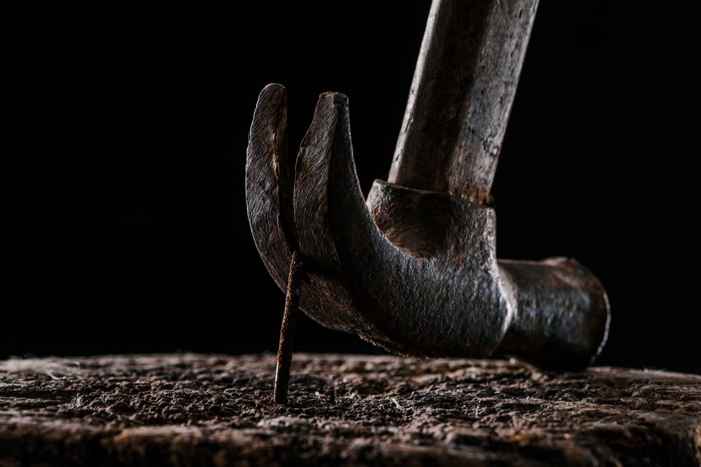  close up view of vintage rusty hammer and nail in wooden stump isolated on black - Photo, Image