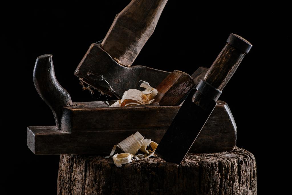 close up view of woodworker plane, axe and chisel carpentry tools on stump isolated on black - Photo, Image