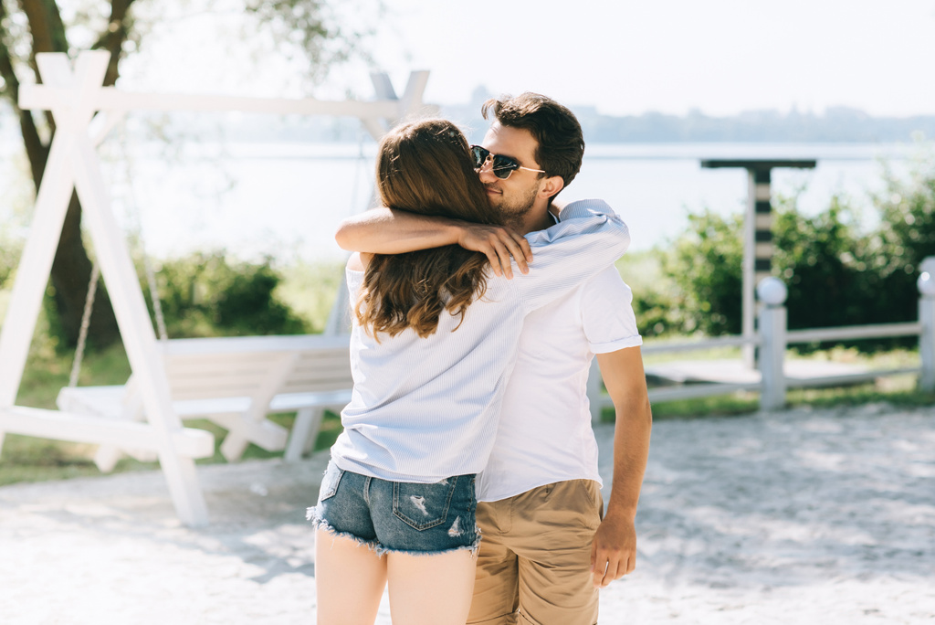 affectionate boyfriend and girlfriend hugging at city beach - Photo, Image