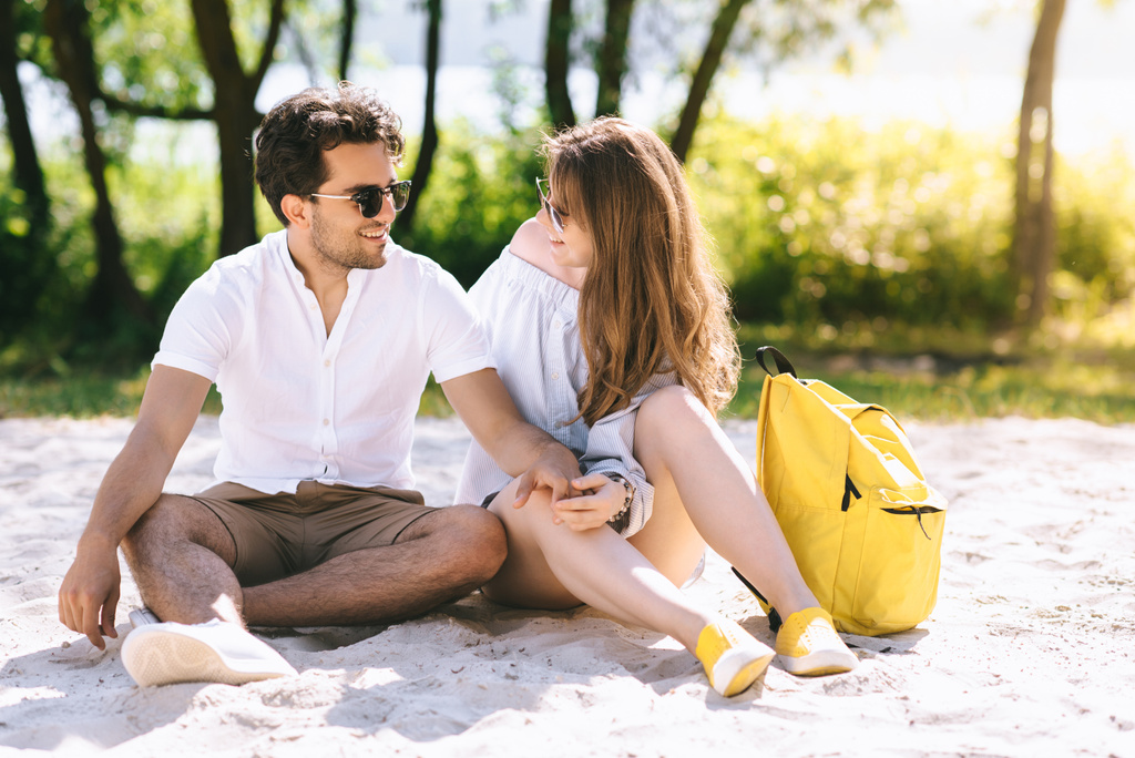 ευτυχισμένο ζευγάρι κάθεται στην πόλη αμμώδης παραλία και κρατώντας τα χέρια - Φωτογραφία, εικόνα