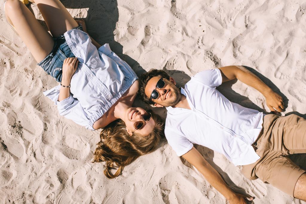 vista elevada de casal sorridente deitado na praia da cidade arenosa
 - Foto, Imagem