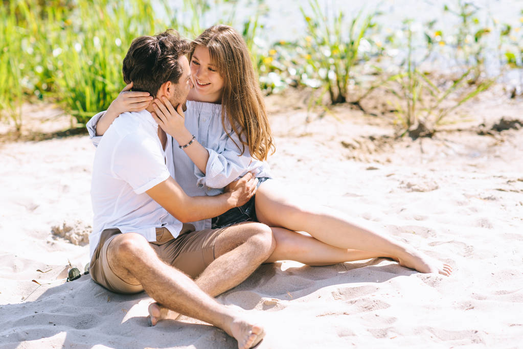 feliz pareja abrazando y yendo a besar en arenosa ciudad playa
 - Foto, Imagen