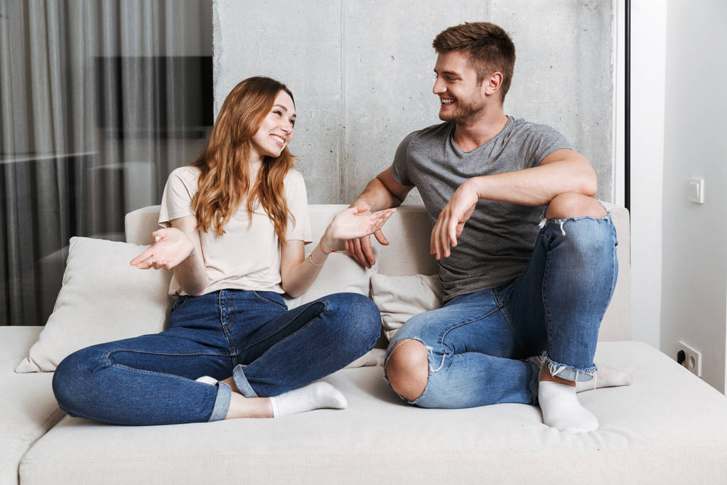 Felice coppia parlando mentre seduti insieme su un divano a casa
 - Foto, immagini