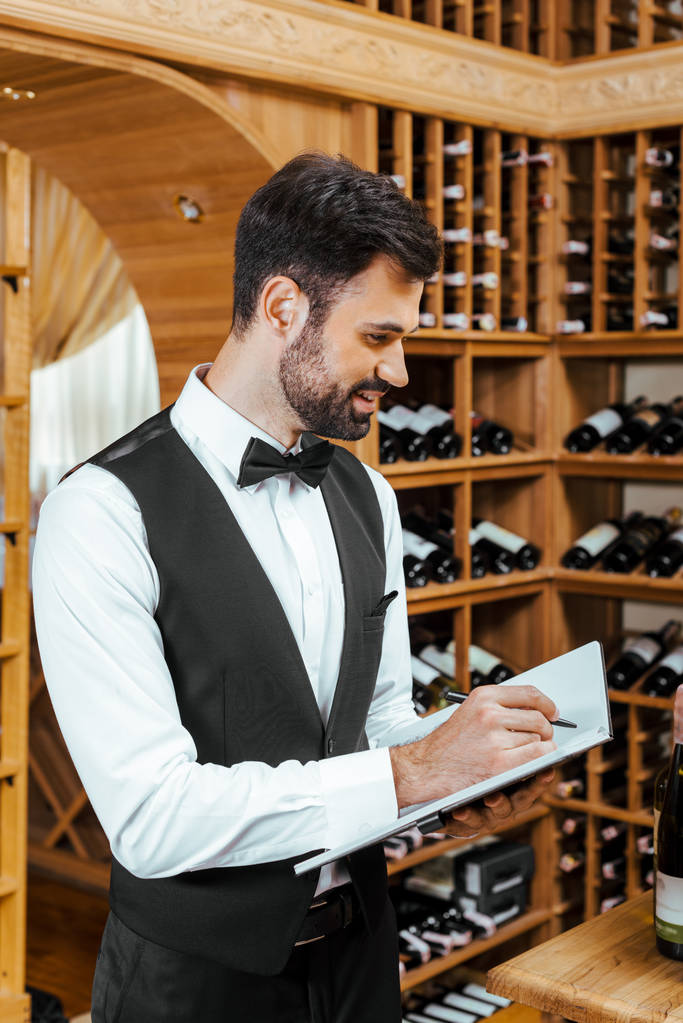 bonito jovem vinho mordomo fazendo notas no vinho loja
 - Foto, Imagem