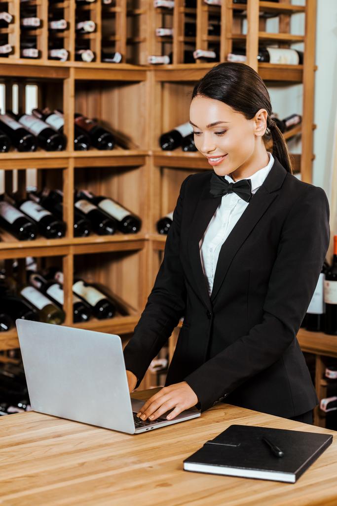 schöne weibliche Wein Stewardess arbeitet mit Laptop in Weinladen - Foto, Bild