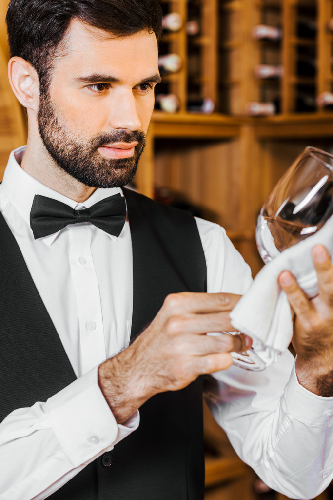 handsome young wine steward wiping glass at wine store - Photo, Image