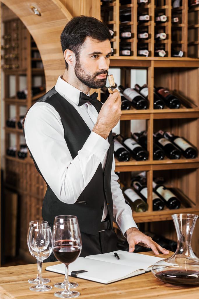 beau jeune steward du vin examinant corc bouteille aromatique après ouverture du vin en magasin
 - Photo, image