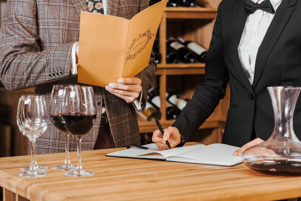 tiro recortado de vinho mordomo escrever notas enquanto o cliente fazendo a ordem na loja de vinho
 - Foto, Imagem