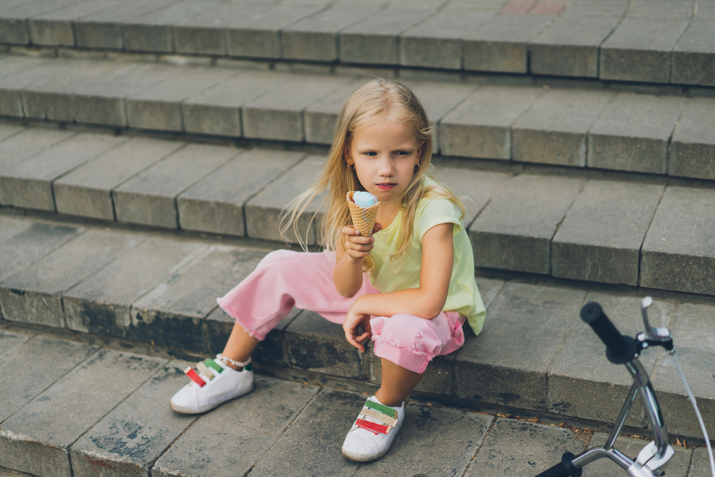 χαριτωμένο παιδί με παγωτό που κάθεται στην πόλη βήματα μόνος - Φωτογραφία, εικόνα
