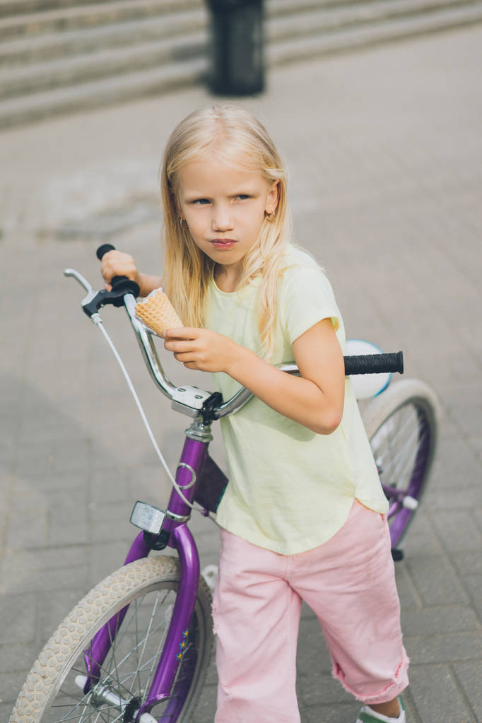 muotokuva suloinen pieni lapsi jäätelöä ja polkupyörää seisoo kaupungin kadulla
 - Valokuva, kuva