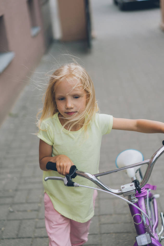 πορτρέτο του μικρού παιδιού με το ποδήλατο, το περπάτημα στο δρόμο - Φωτογραφία, εικόνα