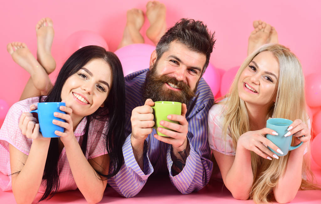 Liebhaber trinken Kaffee im Bett. Liebespaar im Bett. Männer und Frauen, Freunde auf lächelnden Gesichtern, rosa Hintergrund. Mann und Frau in Hauskleidung, Schlafanzug. - Foto, Bild