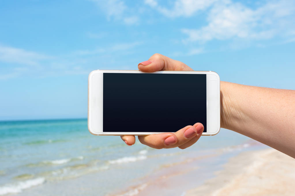Krásná ženská ruka pomocí chytrého telefonu na pláži - Fotografie, Obrázek