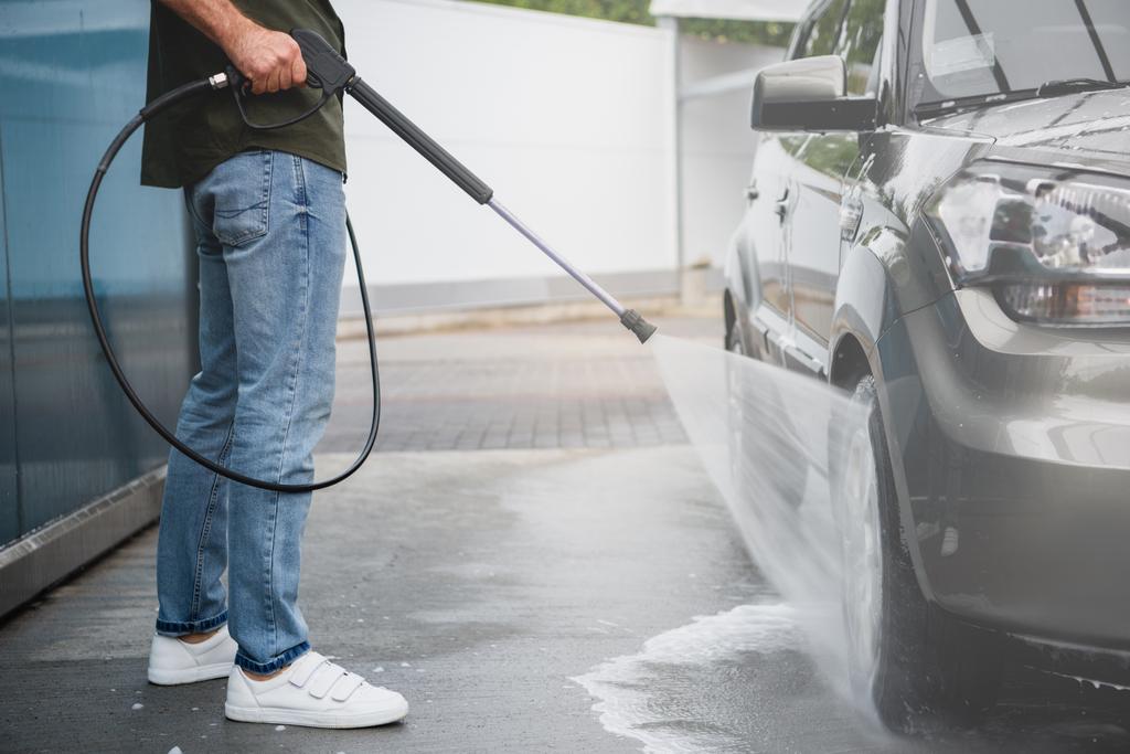 immagine ritagliata di uomo pulizia auto a lavaggio auto con getto d'acqua ad alta pressione
 - Foto, immagini