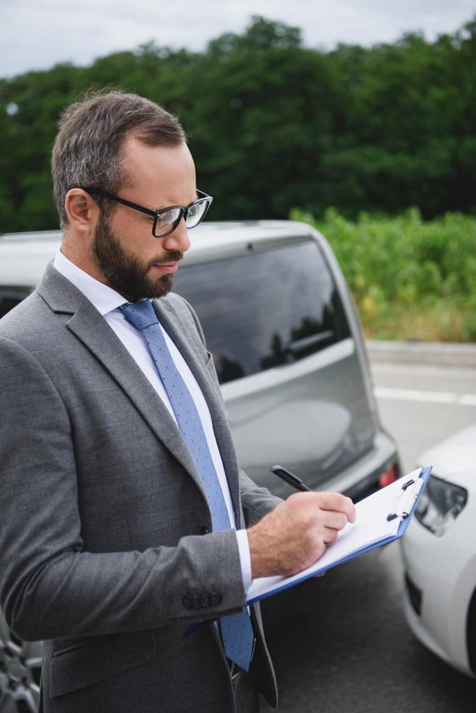 hombre guapo escribiendo algo al seguro de coche después de un accidente de coche
 - Foto, imagen
