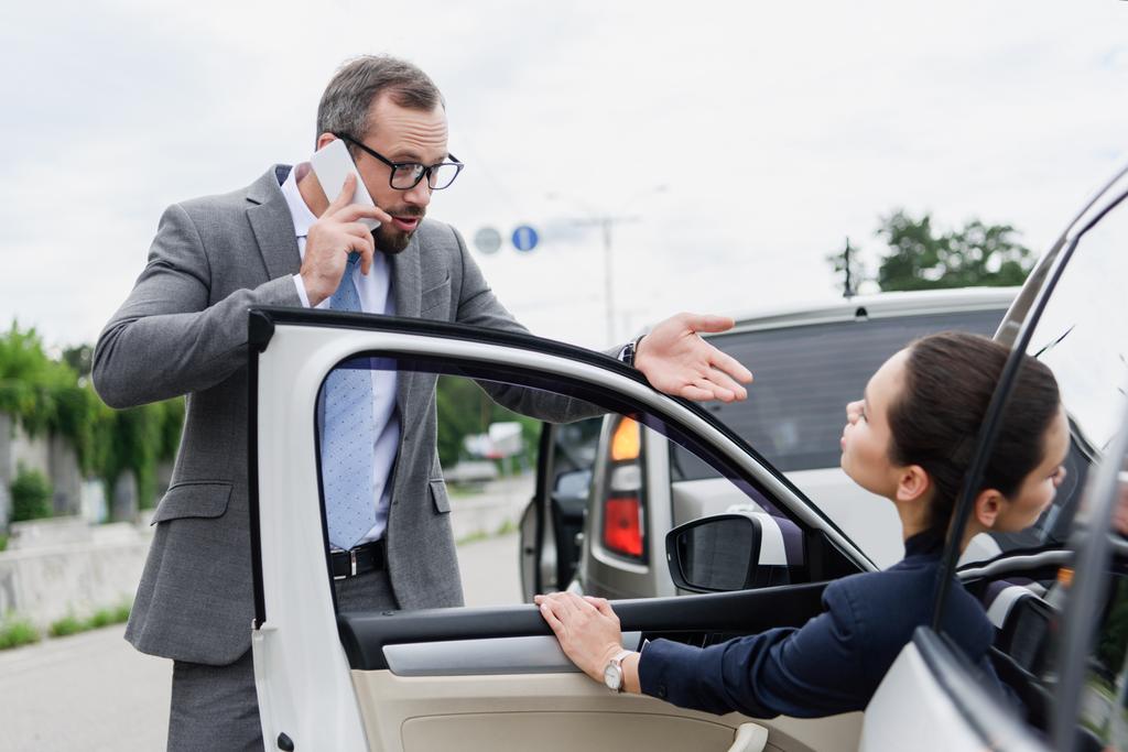 businesspeople quarreling on road after car accident, man talking by smartphone - Photo, Image