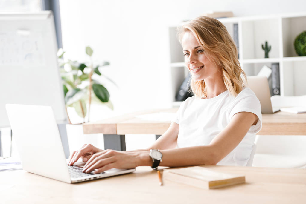 selbstbewusste Geschäftsfrau, die am Laptop arbeitet, während sie am Schreibtisch sitzt - Foto, Bild