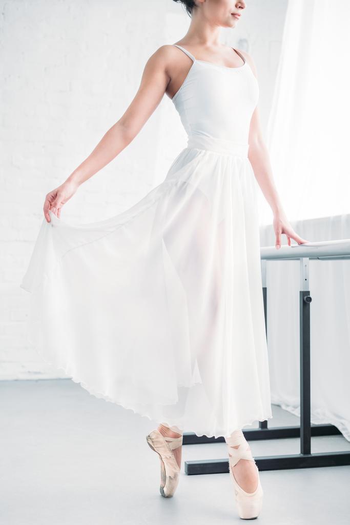 tiro cortado de bailarina jovem elegante em vestido branco praticando balé em estúdio
  - Foto, Imagem