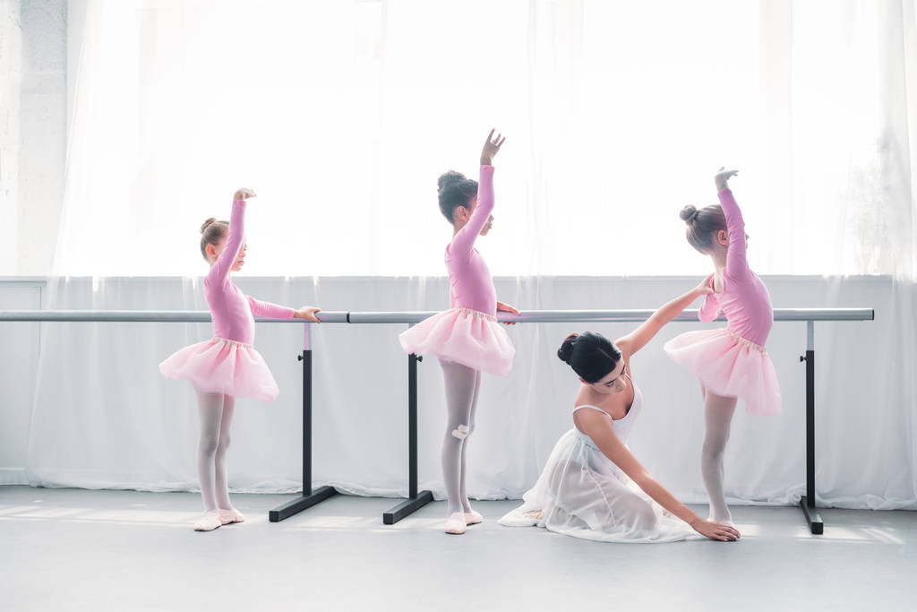 side view of young ballet teacher exercising with kids in ballet school  - Photo, Image