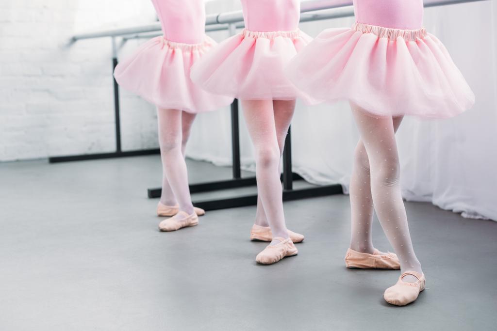 seção baixa de crianças bonitos em saias tutu rosa e sapatos de balé dançando em estúdio
 - Foto, Imagem