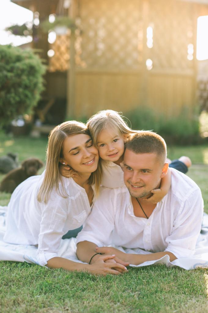 πορτρέτο του χαμογελώντας οικογένεια με μικρή κόρη αναπαύεται στο ύφασμα στο έδαφος μαζί στην πίσω αυλή - Φωτογραφία, εικόνα