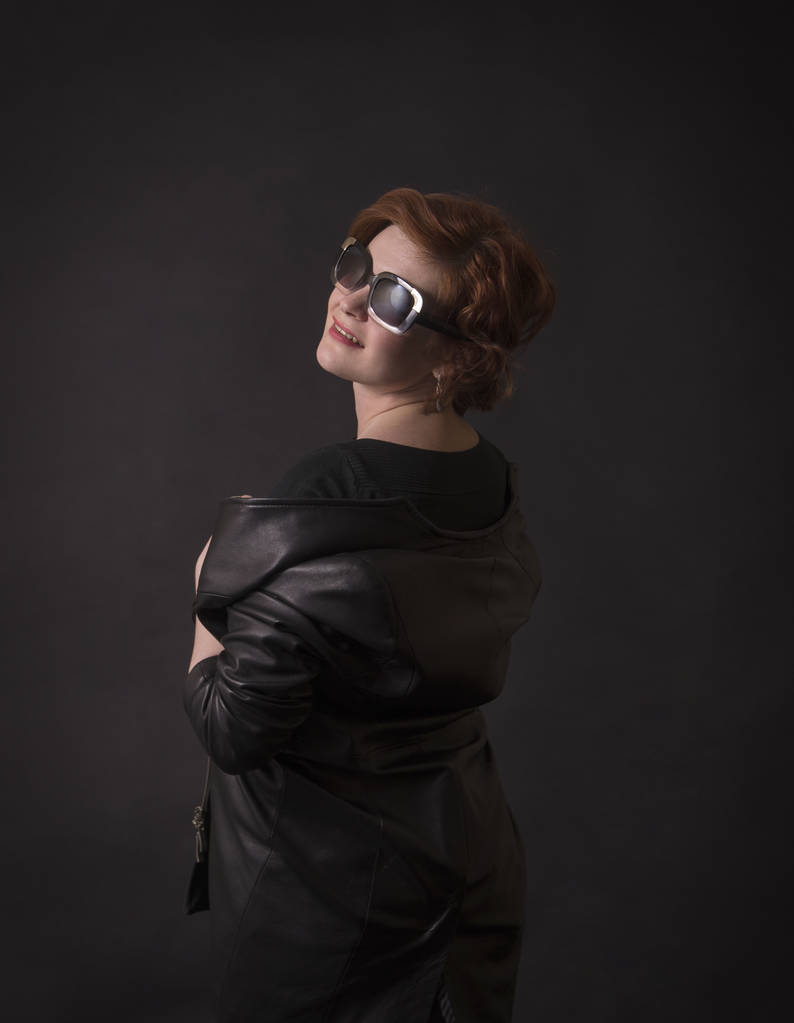 Brune émotionnelle posant dans le Studio dans un manteau en cuir.Image isolée sur un fond sombre
. - Photo, image