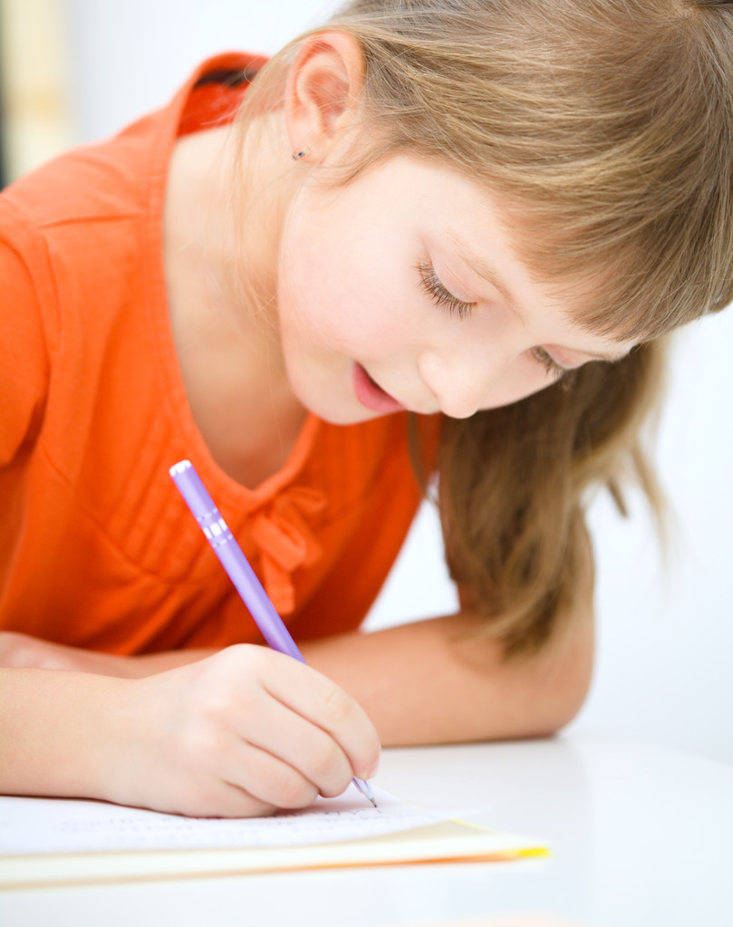 La niña está escribiendo usando un bolígrafo
 - Foto, Imagen