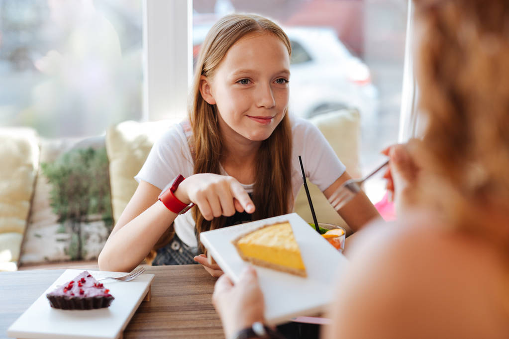 Estudante loira comendo sobremesas com a mãe
 - Foto, Imagem