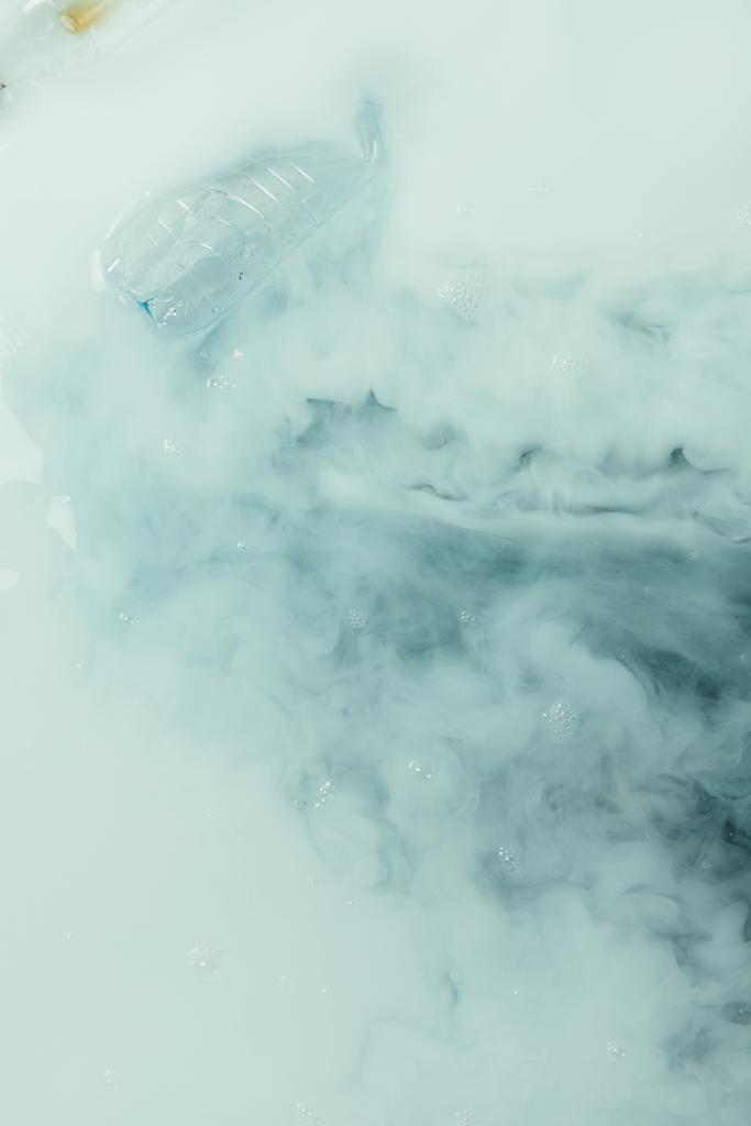 top view of smoke and plastic bottles flowing in water, environment protection concept - Photo, Image